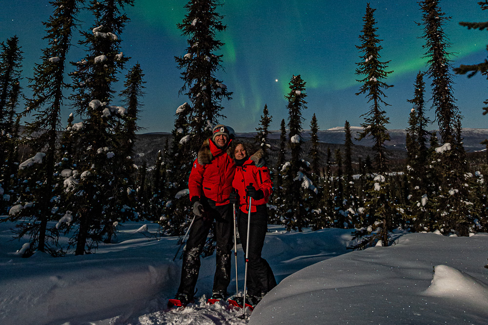 couple aurora winter snowshoe trees northern lights