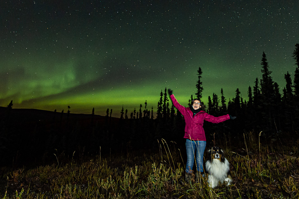 young woman dog fall aurora northern lights portrait